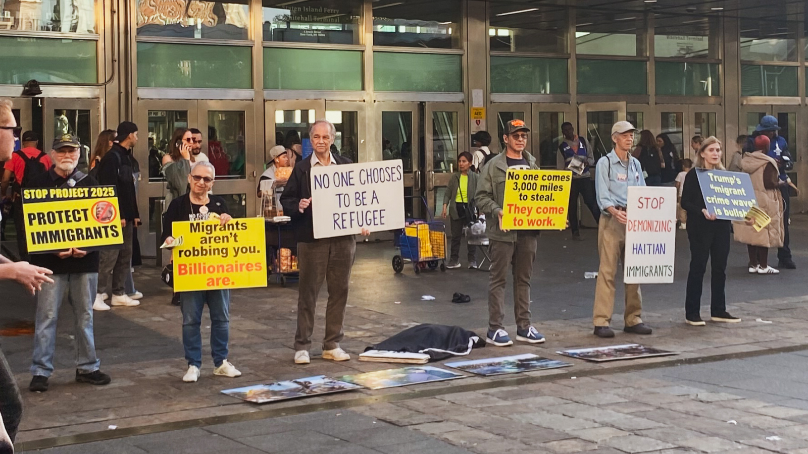 Image of 6 protesters standing outside of Whitehall Terminal protesting the Migrant Issue in New York and against the demonetization of Haitians.